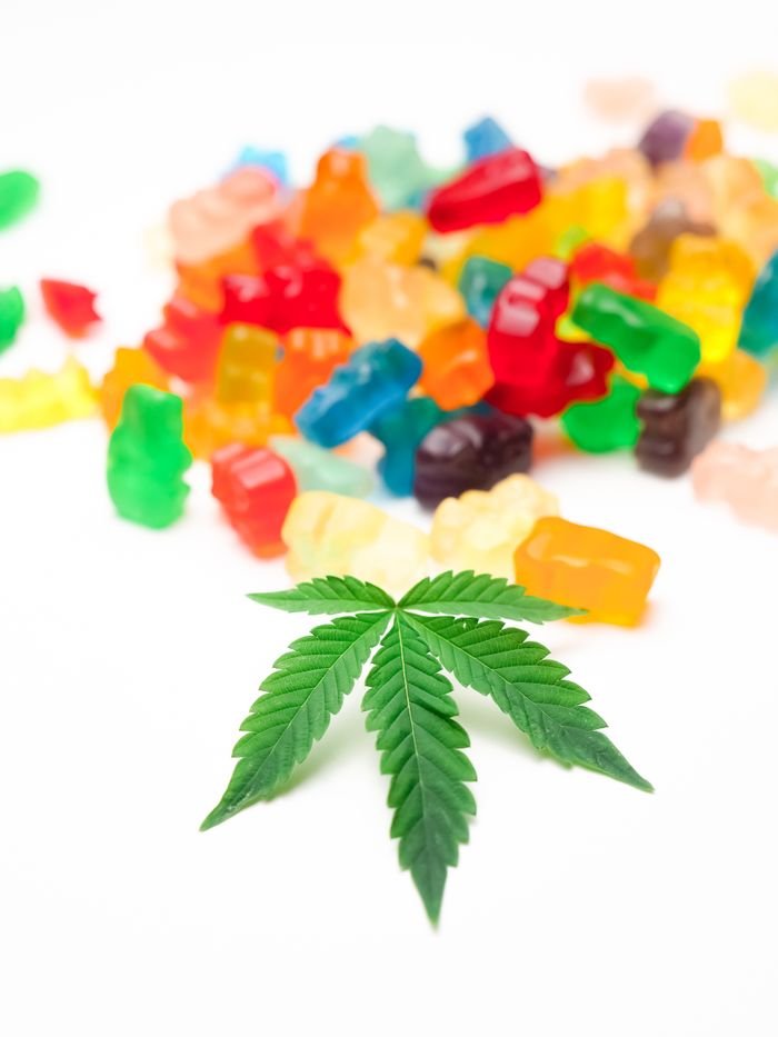 Services A collection of vibrant gummy bears with a single cannabis leaf focused in foreground.